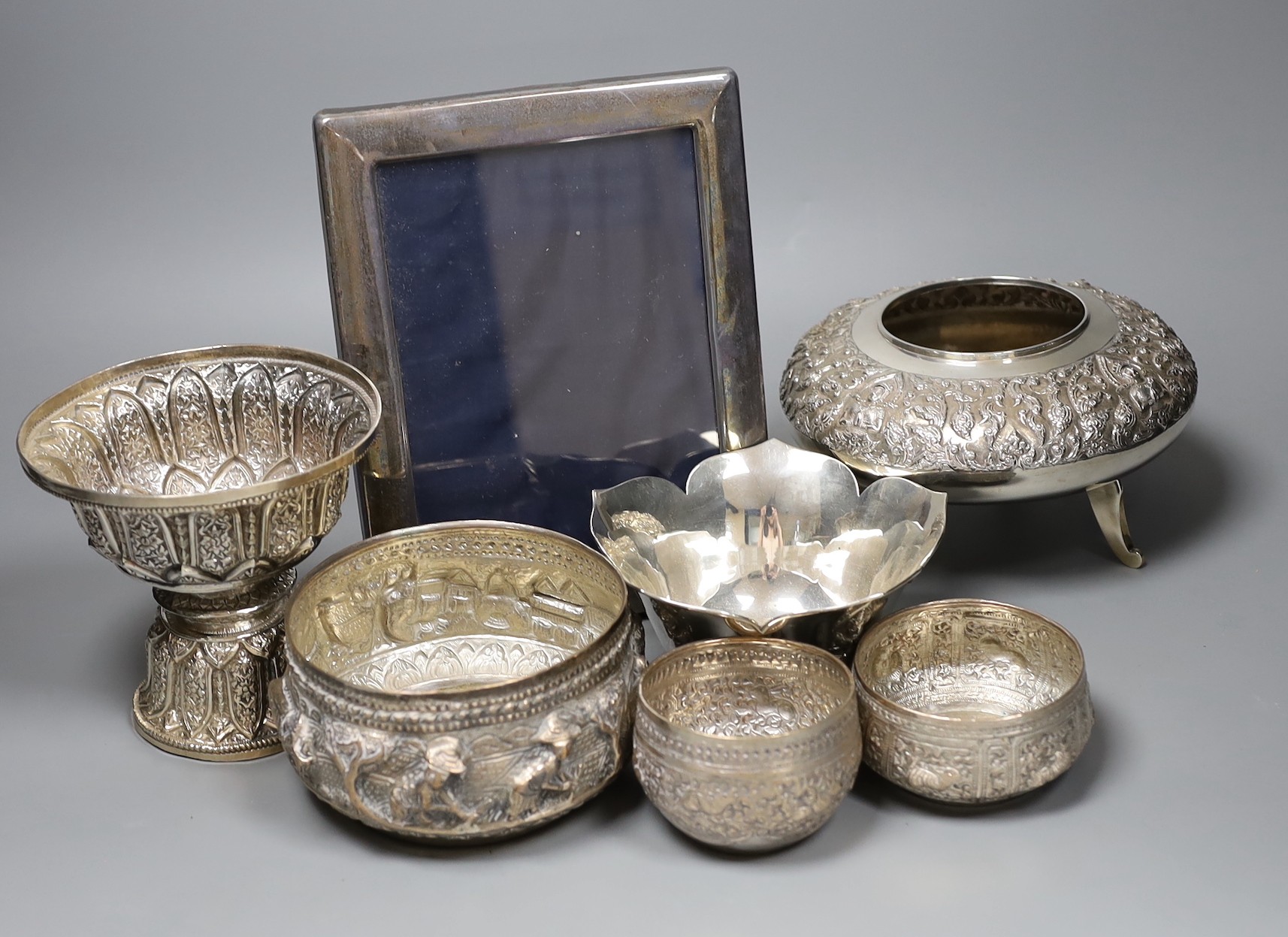 Six assorted embossed Thai white metal bowls, largest 18cm diam., and a silver photograph frame